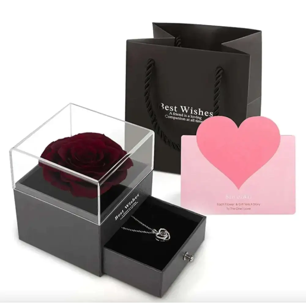 A deep red preserved rose encased in a clear acrylic royal blue preserved rose jewelry gift box on a black base