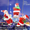 Three plush santa claus figurines with green satchels hanging from golden chains in a claus climbing rainbow toy against cityscape