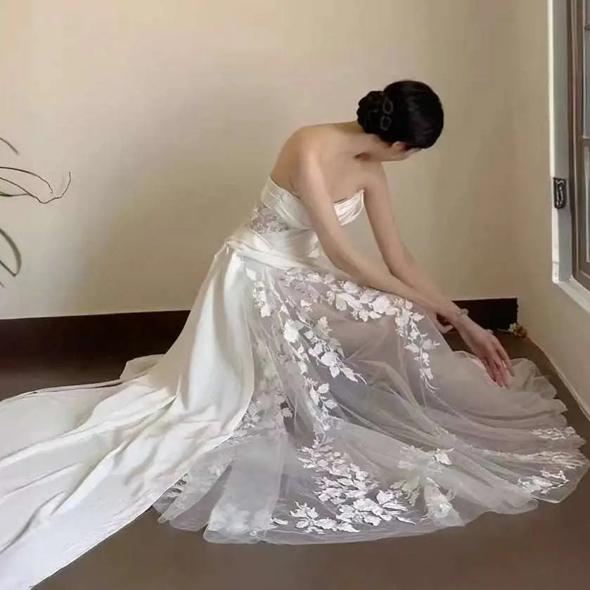 A flowing white satin lace wedding fishtail dress with delicate floral lace appliqués and a lace wedding veil tube top
