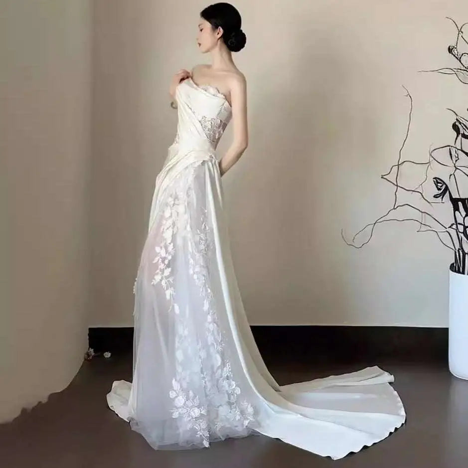 A flowing white satin lace wedding fishtail dress with intricate floral lace detailing and a satin train