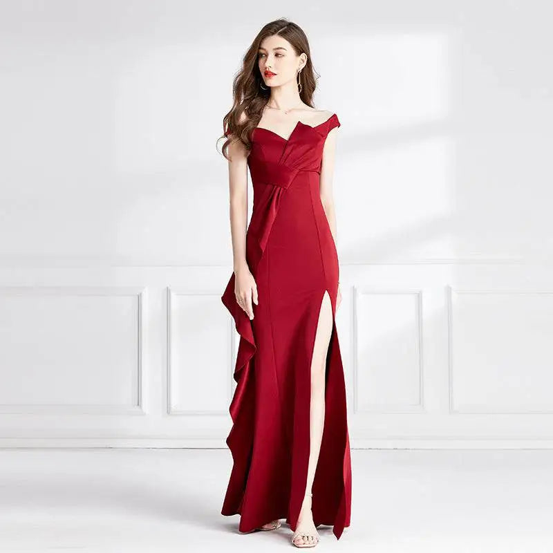 A flowing deep red satin evening dress with sweetheart neckline and high slit featuring asymmetrical ruffle detail