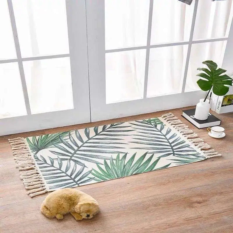 A rectangular beige scandinavian style linen cotton rug with green and gray tropical leaf geometric pattern and tassels