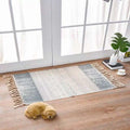 A rectangular scandinavian style linen cotton rug with a gray and cream geometric pattern and tassels on edges
