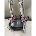 Two pink and black butterfly sculptures rest on a glass platform with silver legs in sequin butterfly latin dance skirt dress