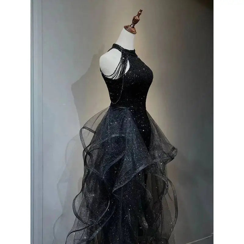 Black sequined halter neck evening dress with layered sheer tulle overlay and flowing tulle skirt for formal occasions