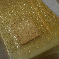 A translucent glass dish on dazzling gold sequined fabric complements the pearl embroidery lace asymmetric dress design