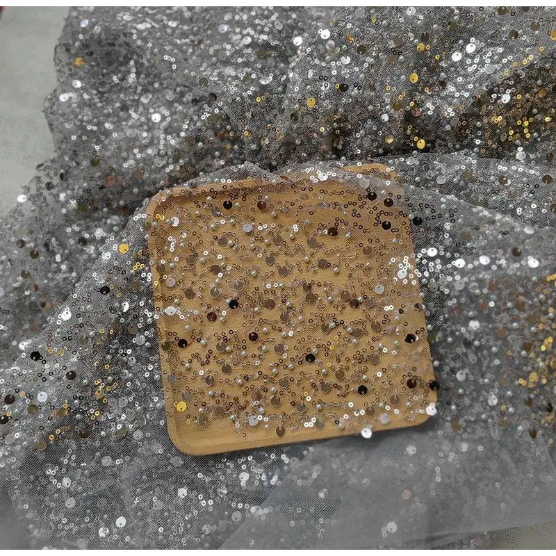 A square wooden tray featuring a dense pattern of dazzling gold sequined pearl embroidery lace suitable for a lace asymmetric dress