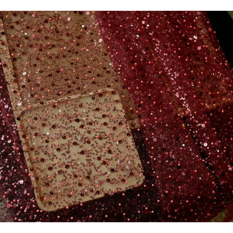 A shimmering rose gold sequined phone case with clear base and intricate beadwork paired with lace asymmetric dress