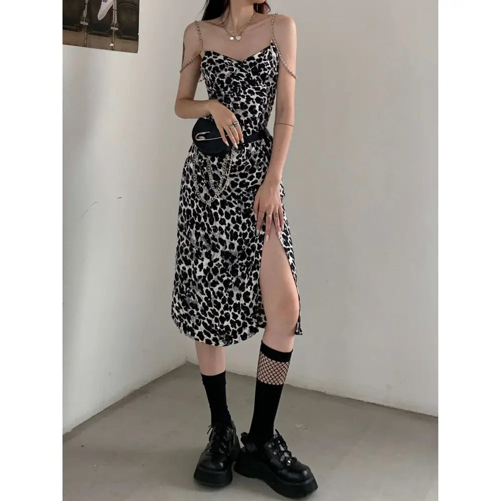 Black and white leopard print satin slip dress with thin spaghetti straps and side slit featuring leopard print chain detail