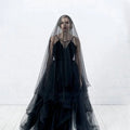 A flowing black veil made of sheer layered tulle drapes elegantly over the model for a sheer bride wedding look