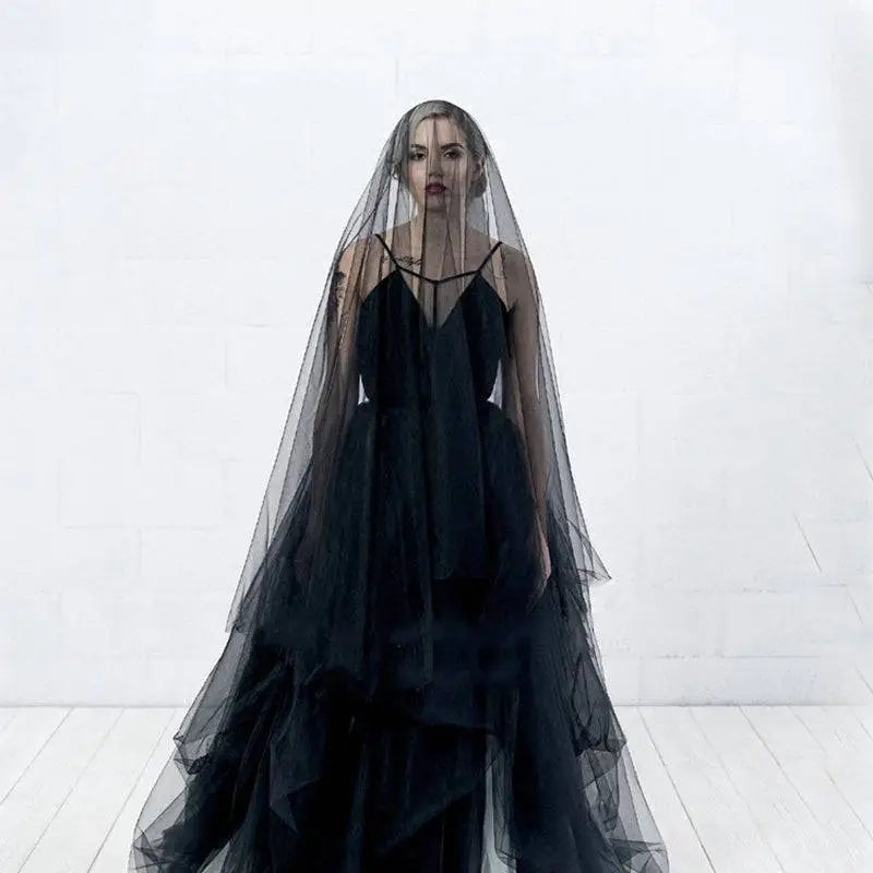 A flowing black veil made of sheer layered tulle drapes elegantly over the model for a sheer bride wedding look