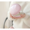 Pink seashell-shaped compact hand warmer with glossy finish and ridged texture for shell rainbow projection hair removal light