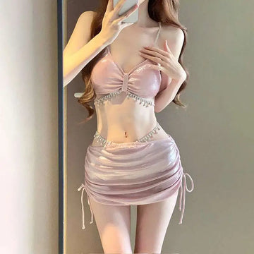 Shimmering pink satin luxury women’s fashion bikini swimsuit with a bow bra top and ruched mini skirt with side ties
