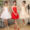 Three women model strapless cream-colored tulle mini dresses with fitted bodice and large bow at the waist for weddings