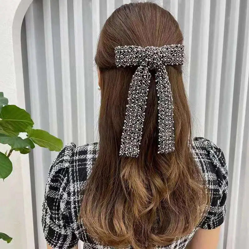Silver beaded bow hair clip featuring sparkling metallic pearls and glass diamonds for an elegant hair accessory