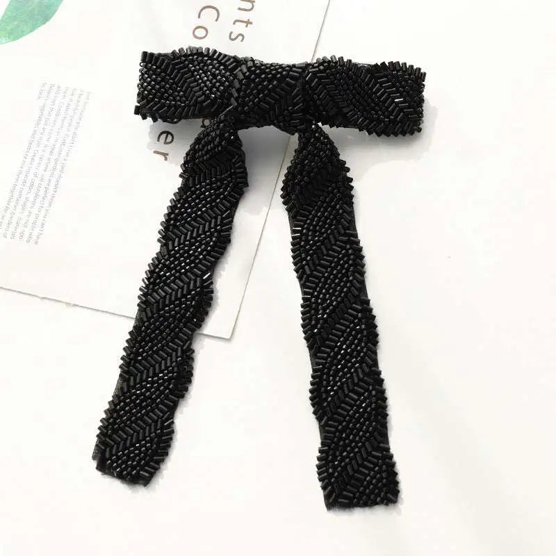 Black beaded bow with herringbone pattern paired with silver beaded bow hair clip adorned with glass diamonds