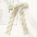 An elegant silver beaded bow hair clip with ivory texture and shimmering glass diamond accents