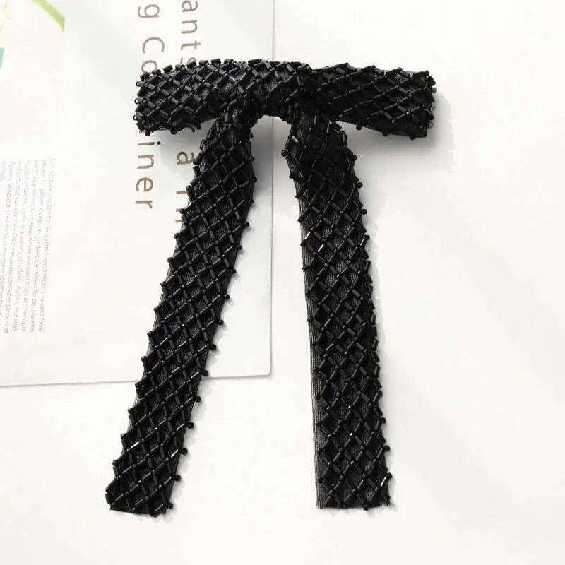 Black beaded bow hair clip with diamond-patterned mesh design and silver glass diamond accents for elegant styling