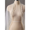 A delicate white sheer long bridal cathedral veil adorned with silver beads and cascading pearl strands along edges