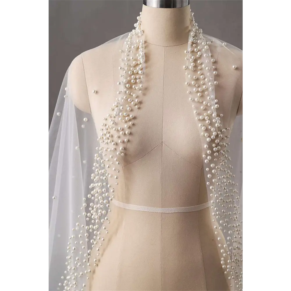 A delicate white sheer long bridal cathedral veil adorned with silver beads and cascading strands of pearls