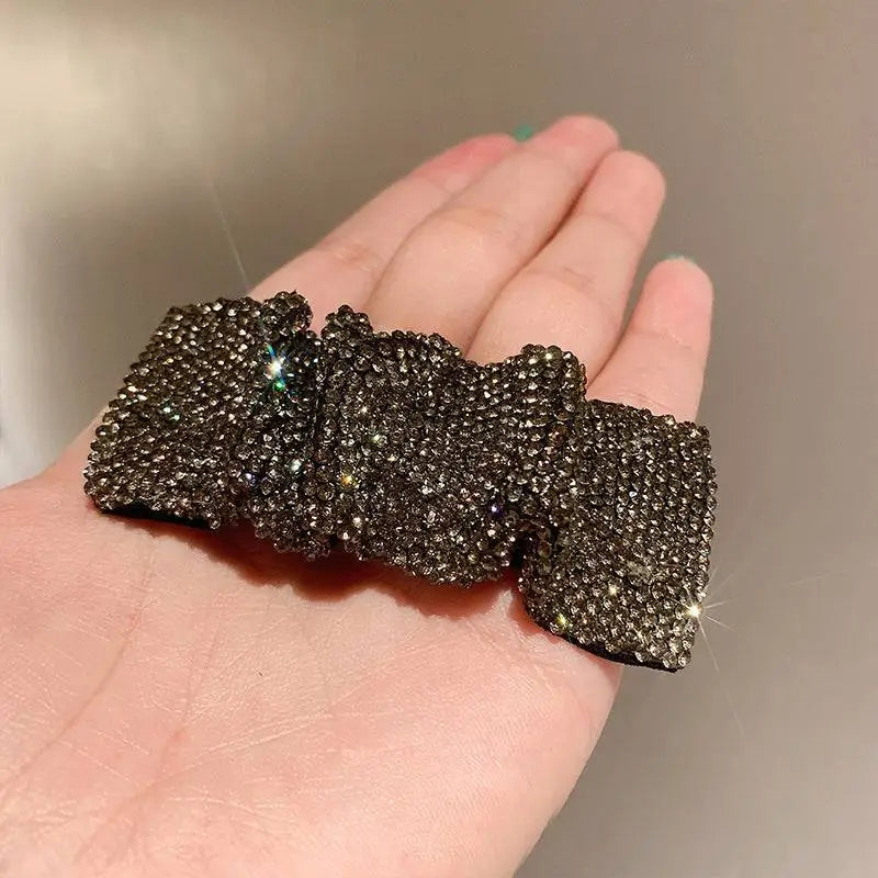 A sparkling black rhinestone bow hair clip featuring hot rhinestone details in a silver bow pleated bb clip design