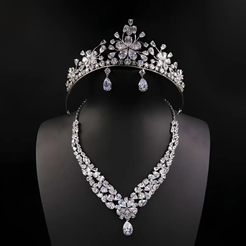 A silver bride headdress crown and matching necklace jewelry suit featuring floral designs and teardrop crystals