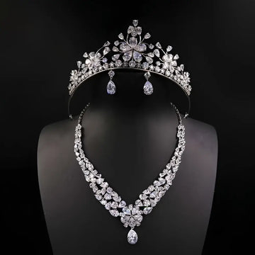 A silver bride headdress crown and matching necklace jewelry suit featuring floral designs and teardrop crystals