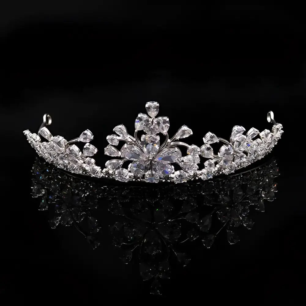 A sparkling silver bride headdress crown with intricate floral designs and clear crystals in a necklace jewelry suit