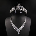 A sparkling silver bride headdress crown with intricate floral designs and matching necklace jewelry suit with teardrop crystals
