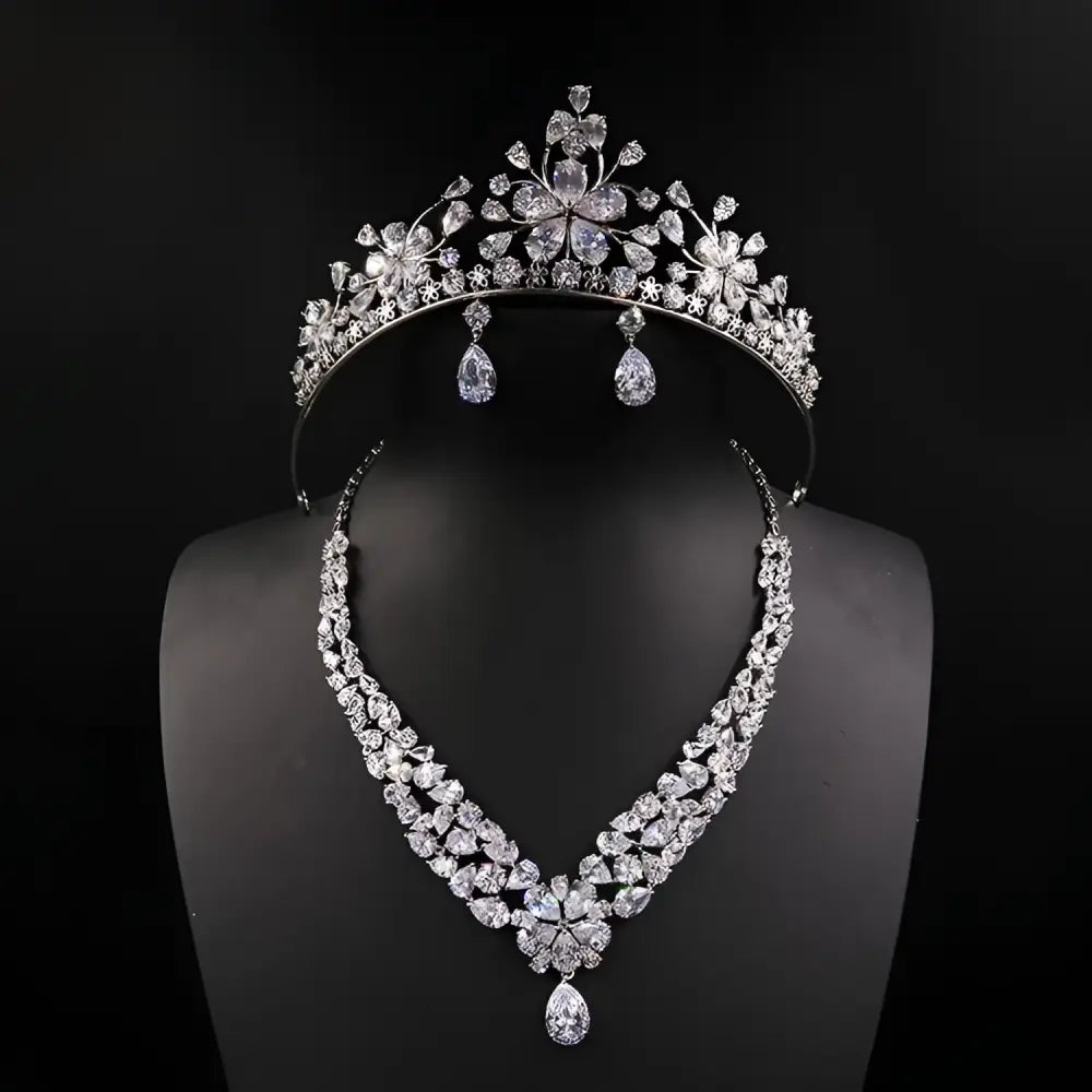 A sparkling silver bride headdress crown with intricate floral designs and matching necklace jewelry suit with teardrop crystals
