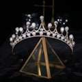 Silver crown rhinestone delicate tiara with white pearls and diamonds displayed on a gold-framed glass stand