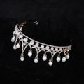 A delicate gold-toned rhinestone pearl tiara with sparkling crystals and dangling pearls as pearl baroque headwear