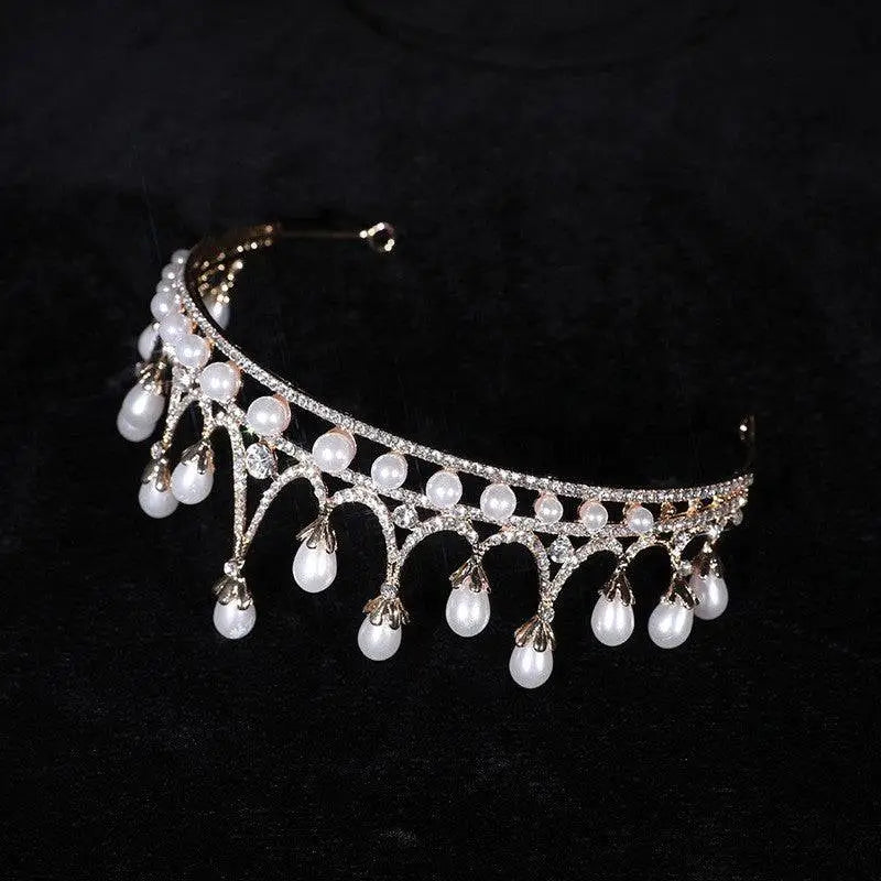A delicate gold-toned rhinestone pearl tiara with sparkling crystals and dangling pearls as pearl baroque headwear