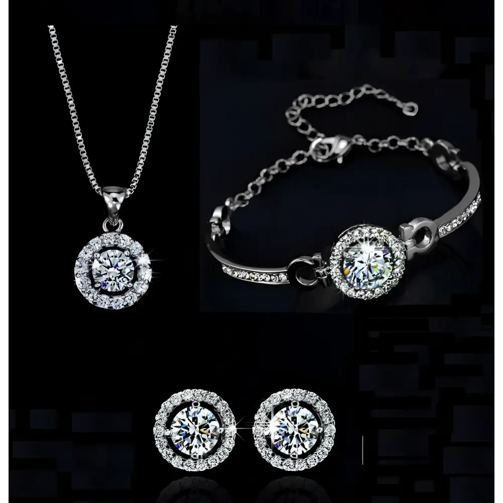 Silver diamond jewelry set featuring silver-toned necklace bracelet and earrings with round-cut clear stones surrounded by accents