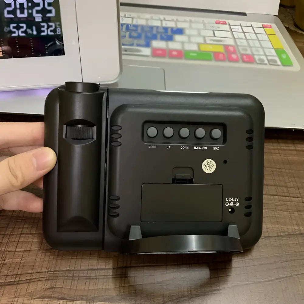 Black plastic digital weather station with vertical adjustment knob and controls for time mode and temperature settings