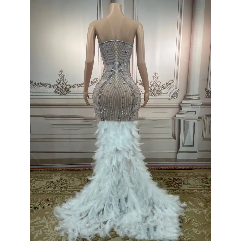 A silver feathered hips sleeveless long gown with intricate beading and a voluminous white feathered hips nightclub train