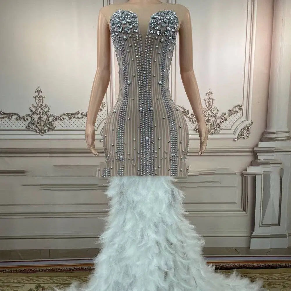 A sleeveless long gown in silver with intricate beadwork and a voluminous white feathered hips nightclub train