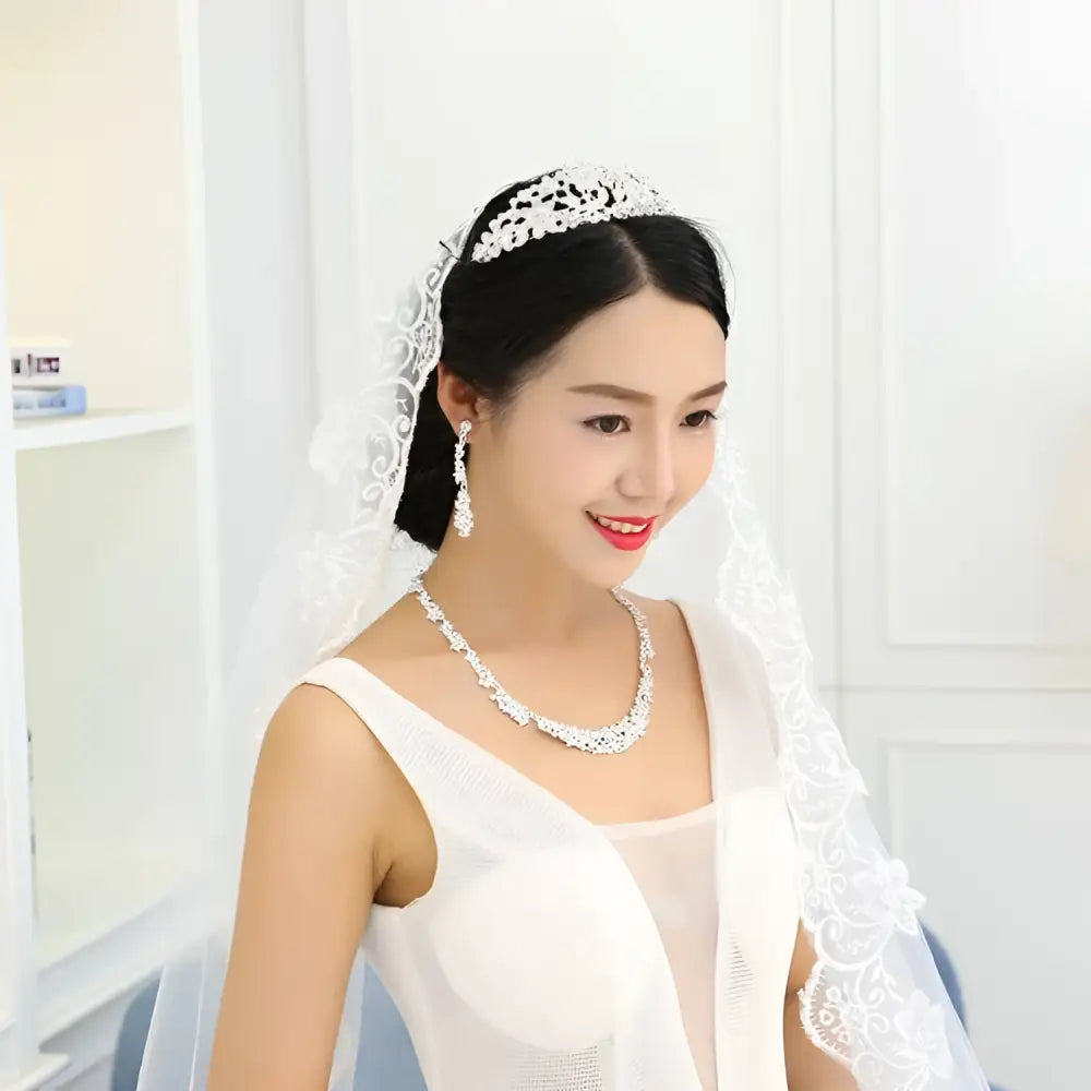 White lace bridal veil with intricate floral embroidery paired with a silver floral jewelry necklace earrings set