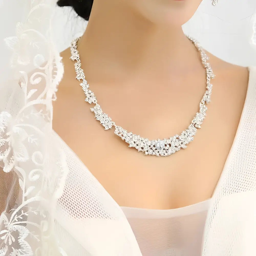 A sparkling silver floral jewelry necklace earrings set with intricate patterns and clear crystals adorns the design