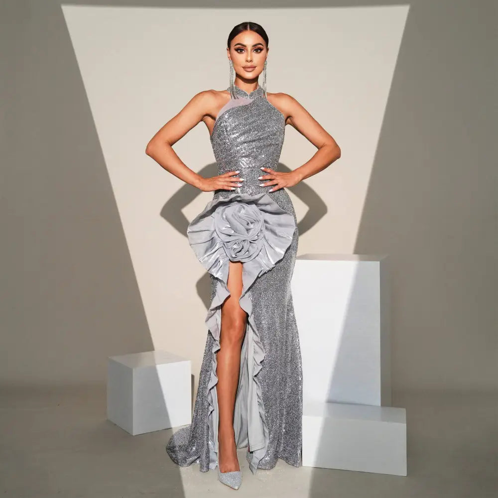 A shimmering silver banquet sequined sheath dress with high neckline, silver floral ruffled waist, and thigh-high slit