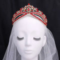 A sparkling red and gold wedding crown headdress with silver floral design and central oval crystal displayed on a mannequin