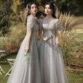 Two women wearing silver gray tulle beaded sisters dress female with off-the-shoulder puffy sleeves and intricate bodices