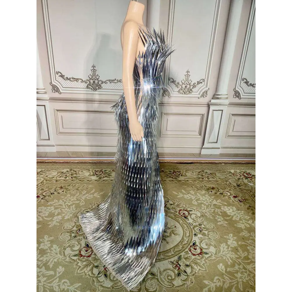 A silver metallic sequined luxury evening dress with a structured silhouette and cascading fringe for stage advanced light use