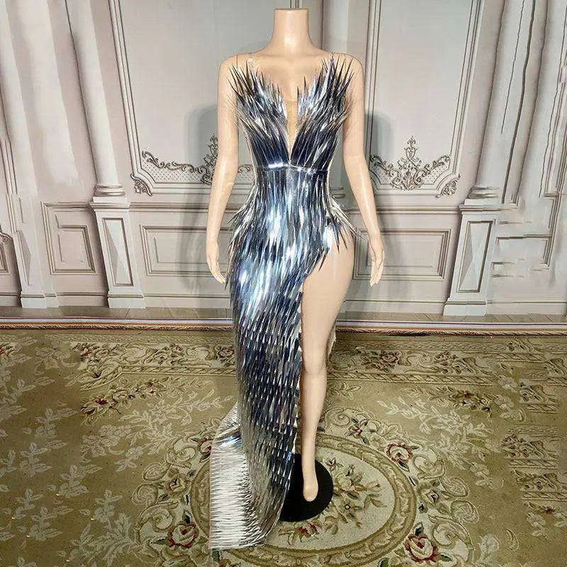 A silver metallic sequined luxury evening dress with shimmering black feather details, plunging neckline, and high slit