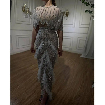 Silver nude feathered evening dress featuring a shimmering silver beaded gown with sheer embellished feather accents