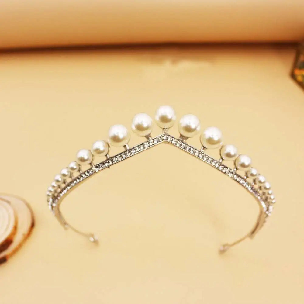 A delicate silver wedding crown alloy adorned with lustrous white pearls and sparkling rhinestones along the band