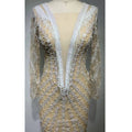 Sheer beige evening gown with intricate white lace appliqués and beaded floral patterns featuring a backless tight fishtail design