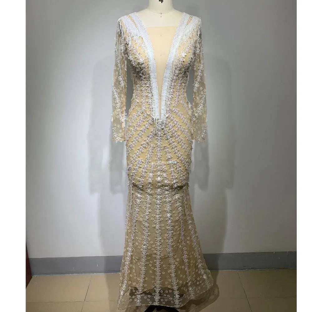 A shimmering champagne-colored backless tight fishtail gown with intricate white lace and long sheer sleeves on a mannequin