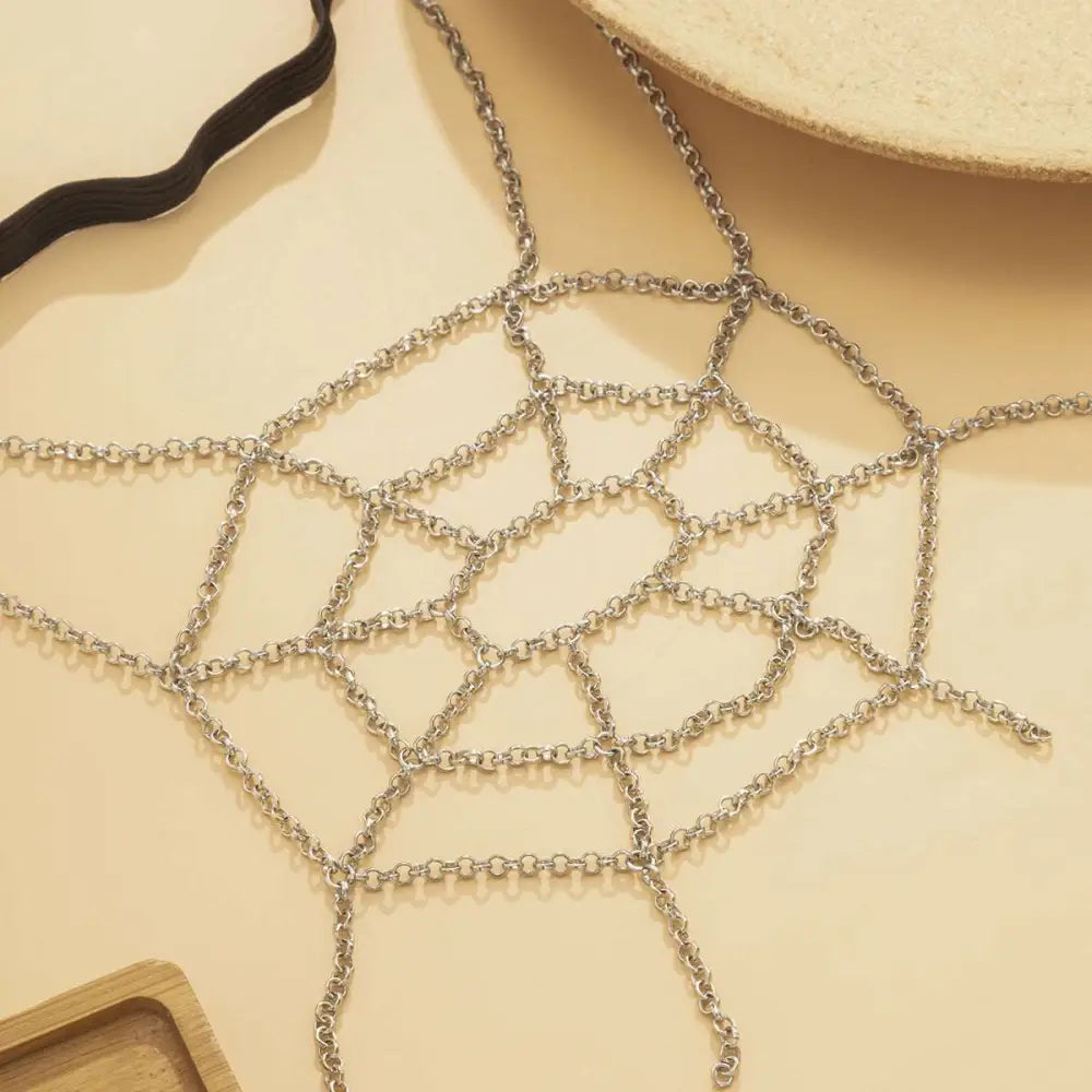 Silver spiderweb geometric body chain with interlocking links forming a delicate silver thigh garter design
