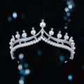 A silver starburst bridal crown baroque tiara with white pearls and embedded crystals in a regal design